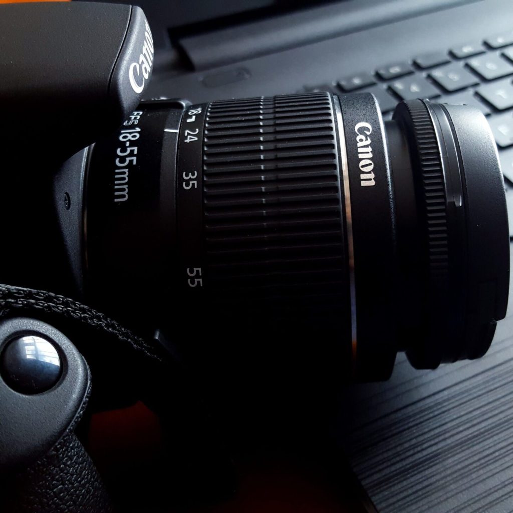 Close-up of a black DSLR camera with lens on a laptop keyboard.